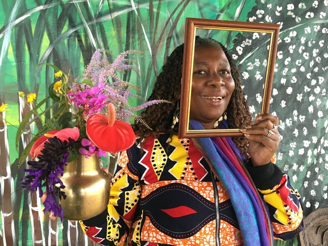 A guest holding a picture frame beside a gold vase of flowers