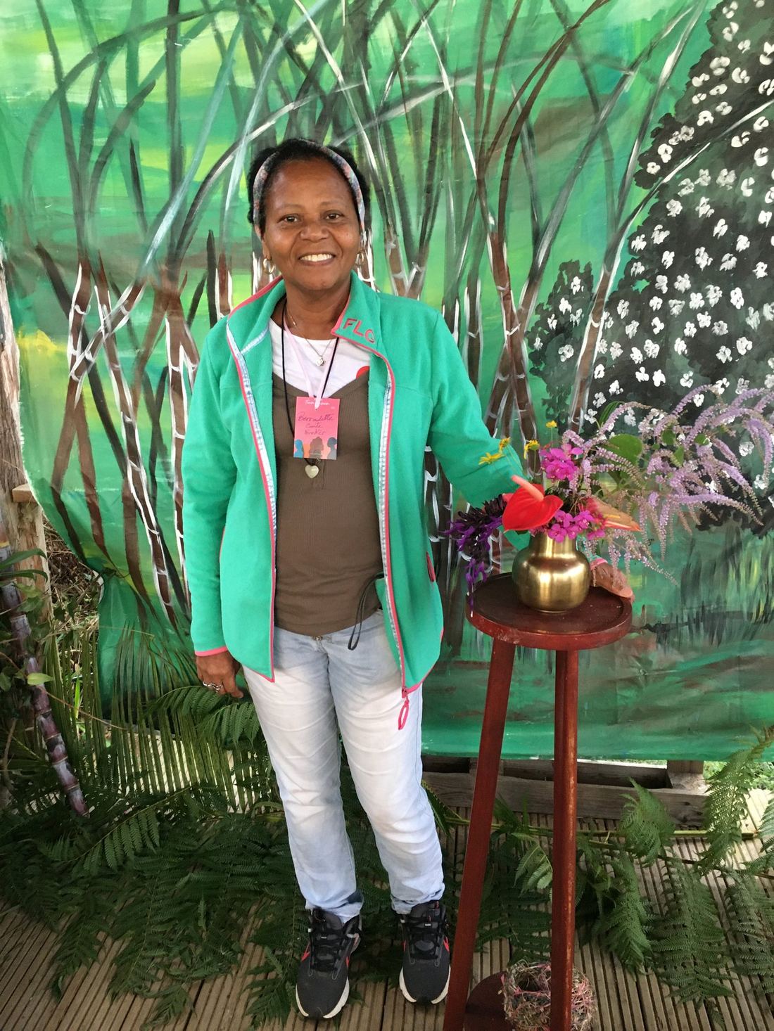 An exhibitor in a green jacket beside a flower arrangement