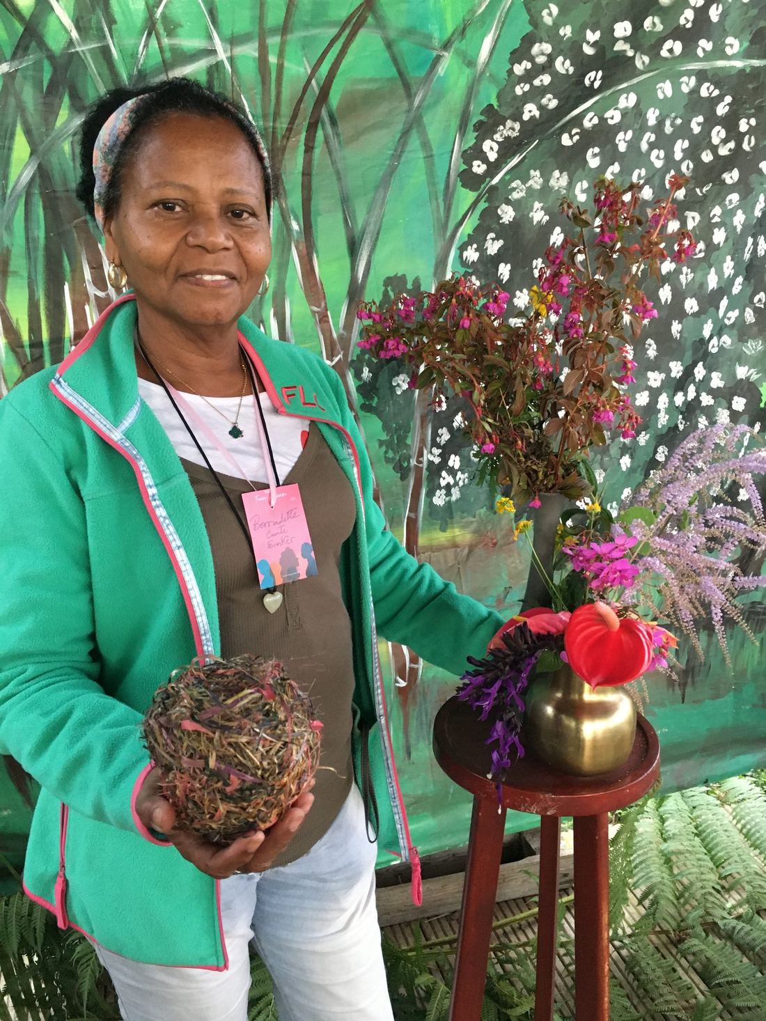 An exhibitor seated beside a small floral display
