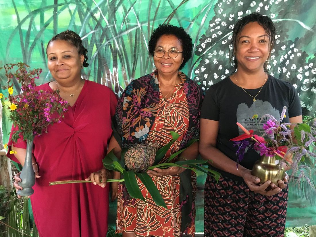 Three women together, each holding a vase of flowers