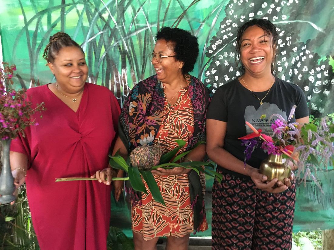 Three women posing together with flowers