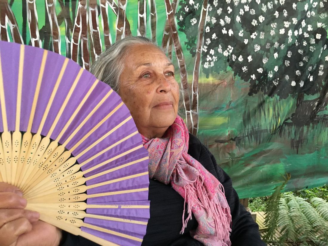 A guest with a purple fan, seated in front of the mural